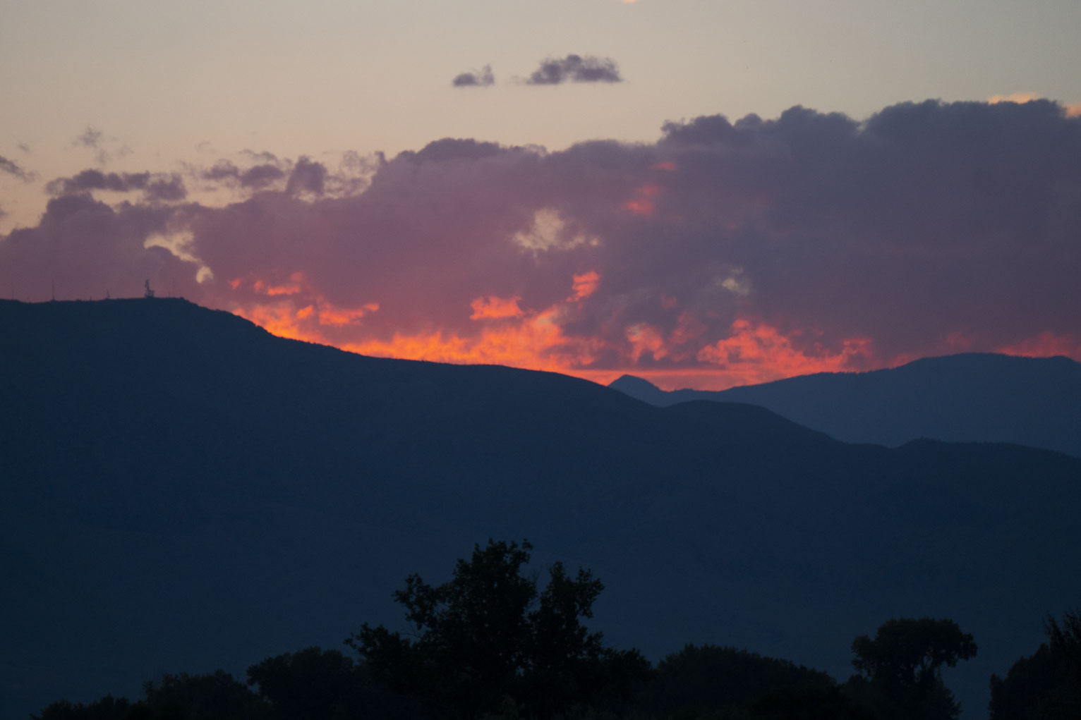 Above the blue mountains bits of the clouds are lit so they look like flames